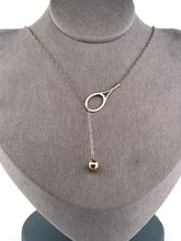 Load image into Gallery viewer, The newest design by Adeline - this unusual necklace is a tennis lovers delight.   The solid gold ball threads through the racket and can be worn higher or lower on the neck.  This piece was hand made in the jewelry district of Los Angeles by a fine jewel craft team.  The racket is 1&quot; long and the ball is 6mm around.  Light yet strong enough to play (and win) in.
