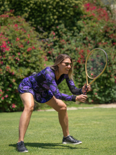 Load image into Gallery viewer, The Angelina Dress is modern yet classy.  This style is in our very limited Purple Pansy print, with a flattering v-neck neckline.  This soft, silky, and sexy tennis dress has an empire waist and a feminine skirt.
